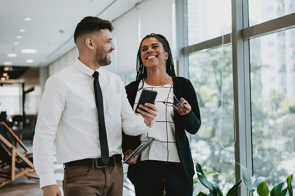 two employees in the company corridor showing smartphone