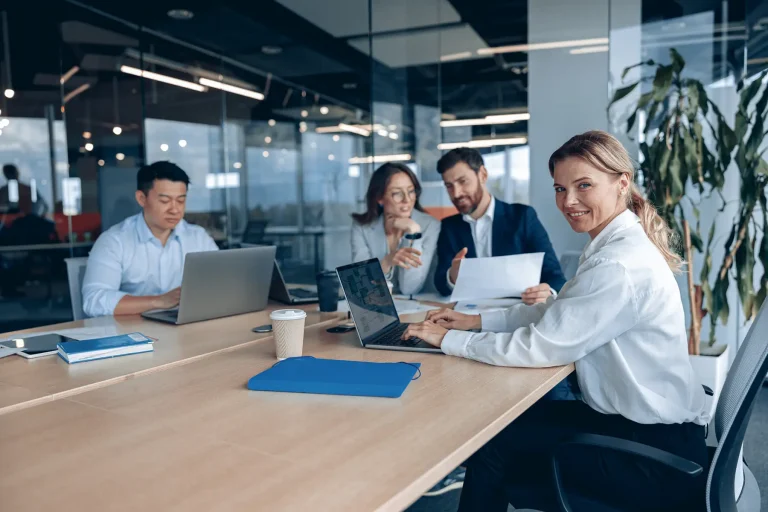 Confident smiling businesswoman sitting at the office with group of colleagues