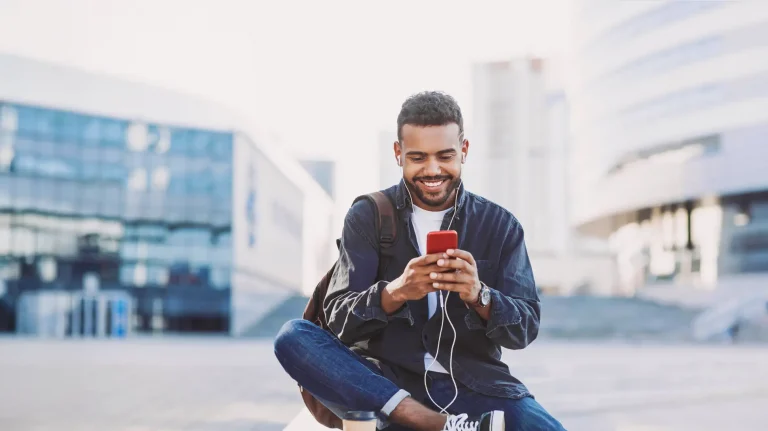 Young professional man using mobile phone outside office building