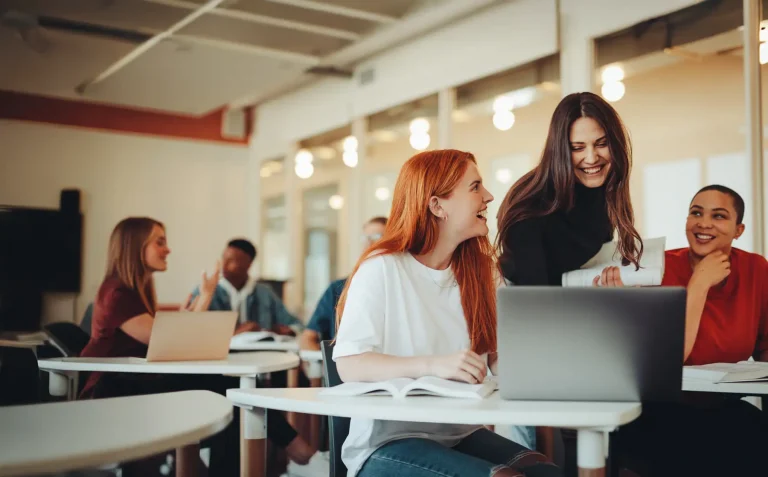 Female student talking with classmates and smiling in lecture room. University students in classroom after lecture.