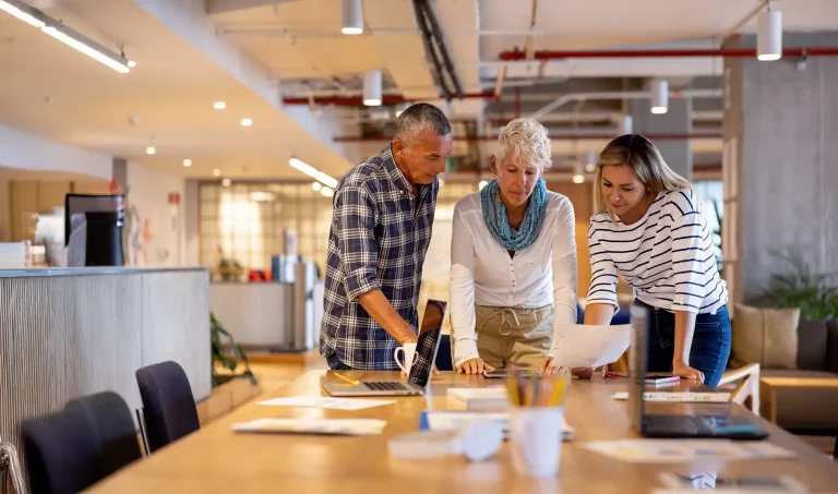 business team brainstorming together at a coworking office and looking at a tablet computer