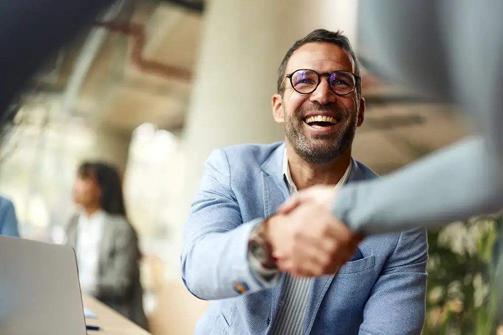 ServiceNow-Insights-2184295789 Happy male entrepreneur greeting his colleague while working in the office.