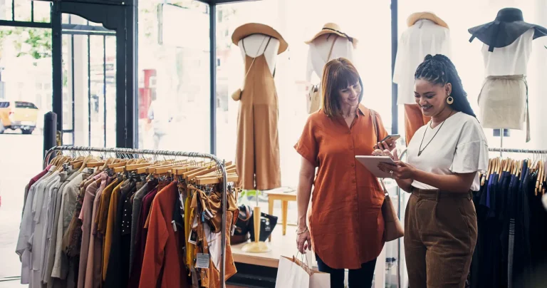 shop assistant using a digital tablet while assisting a customer in a boutique