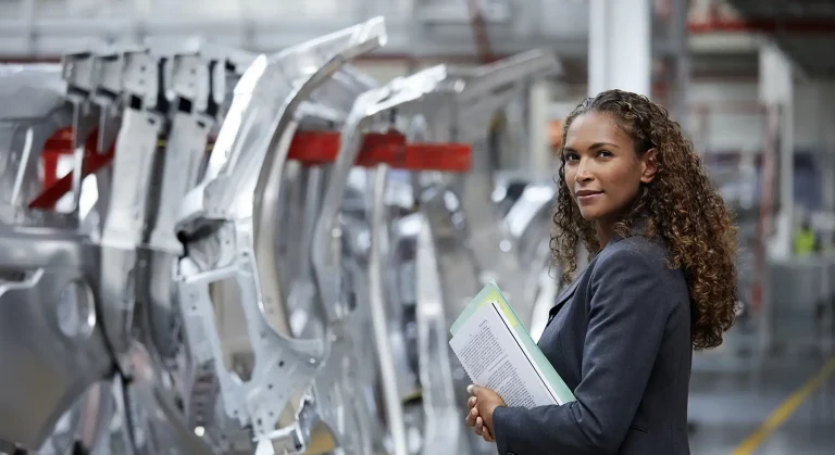 Portrait of confident manager standing by car chassis.