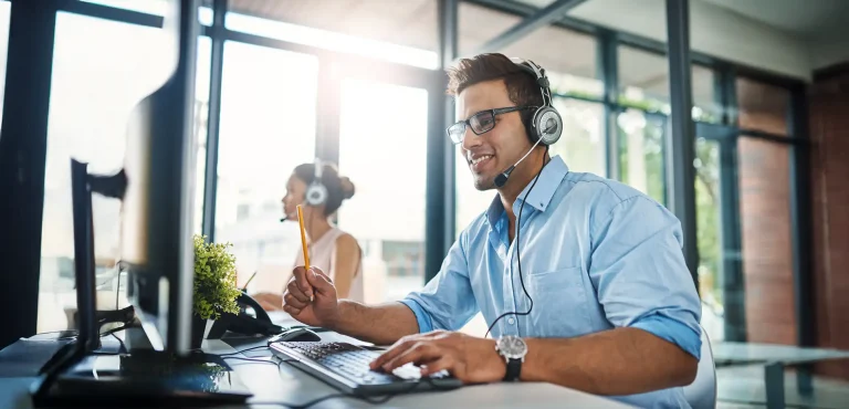 handsome young man working in a call center with a female colleague in the background