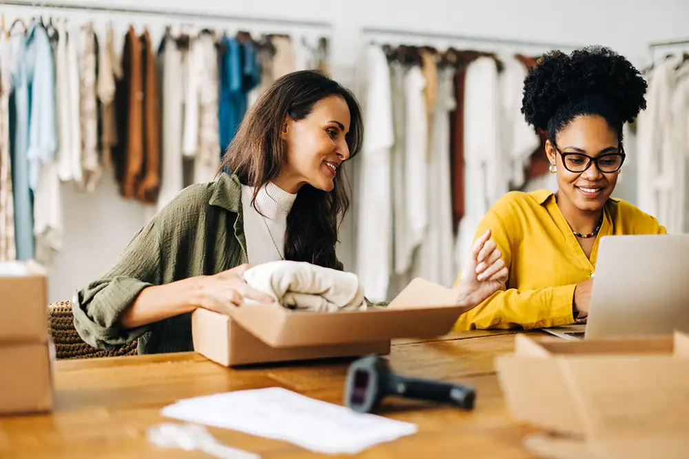 ITSM-1742458874 Business women launching an ecommerce site in a clothing boutique store,